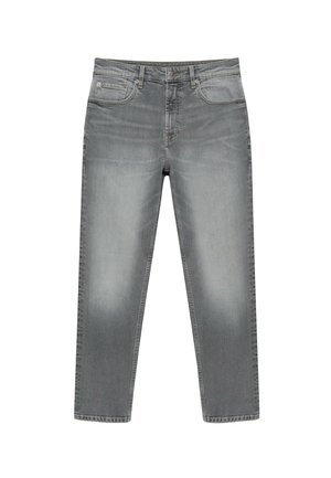 Person iført lysegrå jeans og en hvid skjorte, hvor skjorten delvist er stukket ind i jeansenes bageste linning.