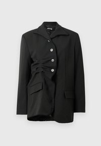 Chaqueta negra con un diseño estructurado, que presenta un gran collar, seis botones y una textura fruncida en la parte frontal, con un bolsillo lateral.