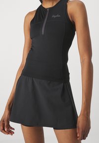 Ensemble de vêtements de sport noirs comprenant un haut sans manches avec une fermeture éclair frontale et un short-jupe. Tissu lisse et extensible avec une silhouette ajustée.