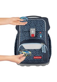 Zaino blu navy con motivo a zigzag, dettagli grigi, tasca anteriore con zip e charm a forma di auto della polizia rimovibile. Dotato di chiusura sicura e maniglia.