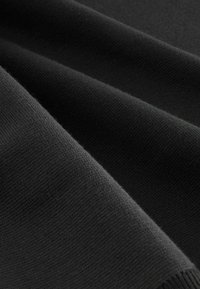 Tejido de punto negro con una textura suave, que presenta una ligera elasticidad y bordes acanalados. Los pliegues generan suaves ondas en un patrón uniforme.