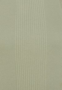 Jasnozielony prążkowany top o miękkiej fakturze, z pionowymi paskami i dopasowanym krojem. Brak wyraźnych elementów metalowych czy ozdobnych.