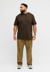 Brown short-sleeve t-shirt paired with light brown corduroy pants. The outfit features a relaxed fit and a textured surface.