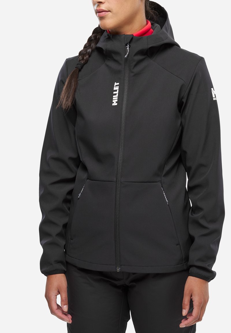Veste softshell noire au design ajusté, capuche attachée, fermeture éclair et deux poches latérales ; présente des logos sur la poitrine et la manche.