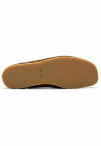 Ruskea kumipohja, jossa on kuvioitu pinta ja valkoinen korostusnauha reunassa. Brändin logo "Clarks" on kohokuvioitu pinnalle.