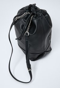 Borsa a tracolla in pelle nera con cordino, top annodato, hardware in catena argentata e tracolla regolabile. Presenta una texture liscia.