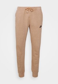 Beige sweatpants i texturerat tyg, med elastisk midja och dragsko samt sidofickor. Litet svart Nike-logotyp på låret.