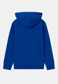 Blå huvtröja i mjukt tyg, med en känguruficka, ribbade ärmslut och en avslappnad passform. Inga mönster eller hårda detaljer synliga.