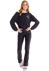 Black off-shoulder sweatshirt with long sleeves, paired with high-waisted black leggings. Red sneakers complete the outfit.
