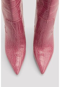 Bottes hautes jusqu'au genou en cuir embossé effet croco rose, avec un bout pointu et une surface texturée, dotées d'un design sans coutures et de détails matériels minimalistes.