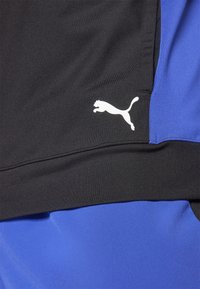 Svarte og blåidrettsshortser med en glatt tekstur, med en hvit Puma-logo og kontrasterende fargeblokker på sidene.