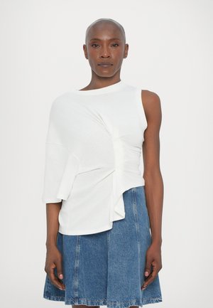 Valkoinen lyhythihainen paita, jossa on laskostettu kangas ja epäsymmetrinen helma, yhdistettynä farkkuhameeseen. Sileä pinta; minimalistinen muotoilu.