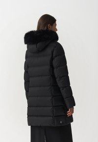 Giubbotto imbottito nero con cappuccio e bordi in pelliccia sintetica. Presenta un design trapuntato, maniche lunghe e tasche laterali. Tessuto morbido e liscio.