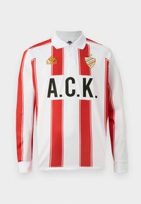 Dlhý rukáv polo tričko, biele s červenými vertikálnymi pruhmi, s čiernym nápisom "A.C.K." a zlatým logom "Kappa" na ľavej hrudi.