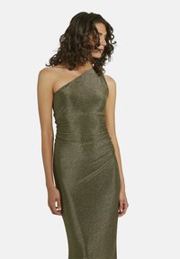 Robe de soirée asymétrique verte en paillettes avec des détails froncés, silhouette ajustée et texture douce, mettant en valeur la silhouette du corps.