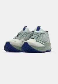 Heledad rohelised matkasussid, millel on tekstureeritud sisenemine, tumesinised detailid ja robustne, mustriline põhi haardumiseks. Stiilsed disainielemendid on lisatud.