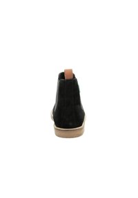 Stivale alla caviglia in suede nero con una linguetta in pelle color tan, suola beige e design minimale. Texture liscia, punta arrotondata e senza motivi o componenti visibili.