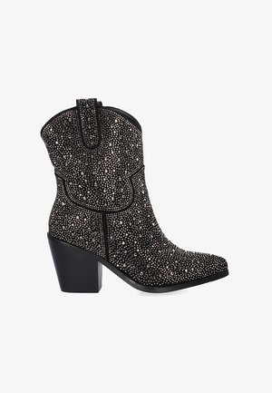 Botas de tobillo estilo vaquero en negro con un exterior brillante de cuentas, puntera puntiaguda y tacón ancho, que presentan detalles de costura sutiles.