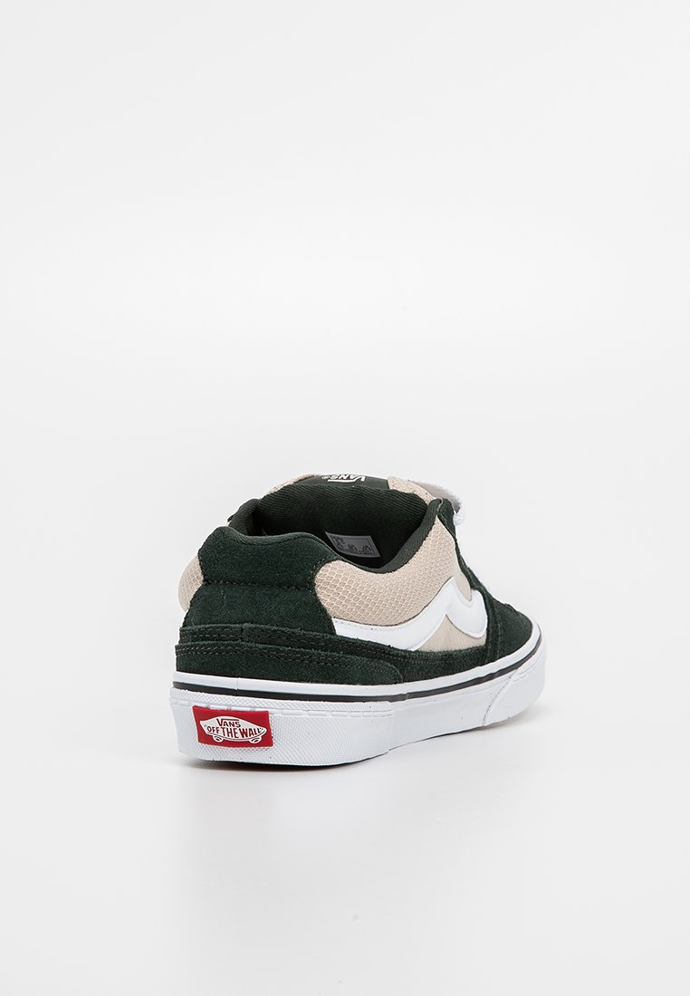 Baskets basses Vans vertes et beiges avec une bande blanche sur le côté, une semelle blanche et un logo rouge "Vans Off The Wall" à l'arrière.