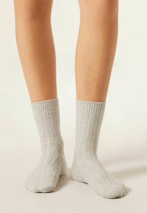 Graue gerippte Socken aus einem weichen Material, mit einem Strickdesign und einer mittelhohen Länge bis zur Wade, ausgestattet mit elastischen Bündchen für einen sicheren Sitz.