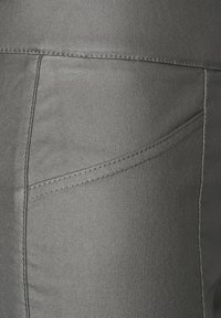 Grå tygbyxor med en slät yta, vinklad framficka och kontrasterande sömmar längs kanterna.