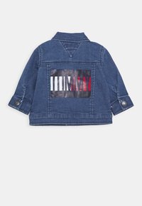 Kurtka dżinsowa w ciemnoniebieskim kolorze z graficznym nadrukiem na plecach w kolorach czerwonym, białym i czarnym. Mankiety na guziki oraz kołnierz zapinany na guziki.