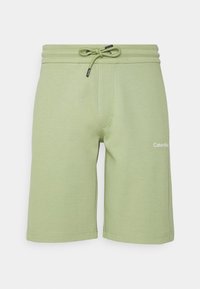 Pantaloni corti Calvin Klein di colore verde chiaro con cintura regolabile e logo sulla coscia sinistra, esposti su uno sfondo bianco.