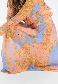 Robe fluide et transparente avec un motif floral orange et bleu, présentant des designs semblables à du bambou. Texture douce et coupe ample, manches longues.