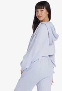 Helleblaue, kurz geschnittene Kapuzenpullover aus strukturiertem Stoff mit oversize Passform, kombiniert mit passenden, strukturierten Hosen mit elastischem Bund.