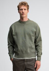 Olijfgroene sweatshirt met geribbelde kraag, manchetten en zoom. Heeft een ronde hals, een gestructureerde stof en een klein logo-label aan de onderzoom.