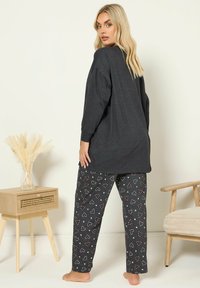 Szara bluzka z długim rękawem zestawiona z czarnymi spodniami w czerwone i białe serca. Miękka tkanina, luźny krój i prosty design.