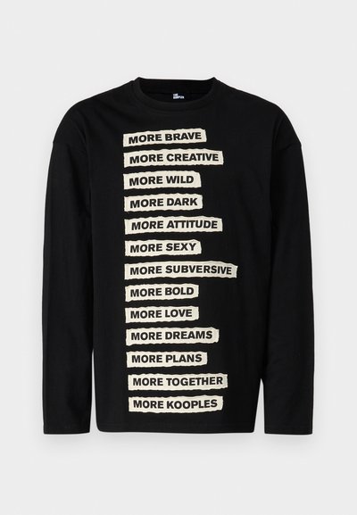 Black long-sleeve t-shirt featuring white text in a cut-out style with various phrases arranged vertically on the front. Soft cotton material.