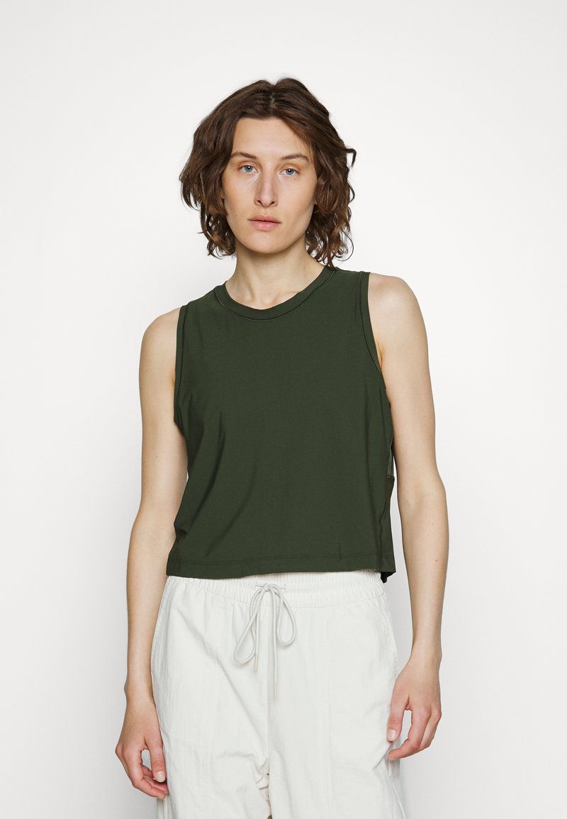Top cropped verde escuro feito de tecido liso, com decote redondo e design sem mangas, combinado com calças de cordão em creme claro.