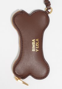 Brązowy skórzany brelok w kształcie kości z złotym suwakiem i złotym napisem „BIMBA Y LOLA” wytłoczonym na powierzchni. Gładka faktura, elegancki design.