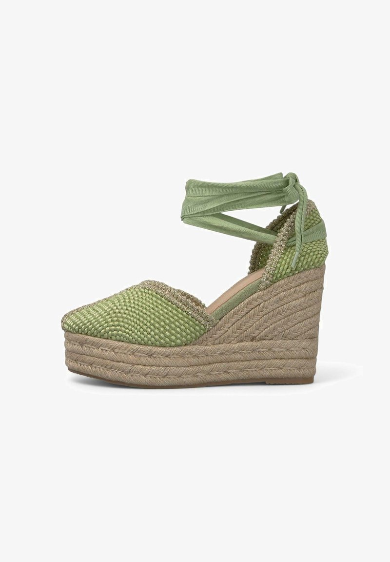 Espadrilla verde con tomaia in tessuto intrecciato, suola in juta intrecciata, dettagli testurizzati e lacci alla caviglia. Accentata da una leggera lucentezza.