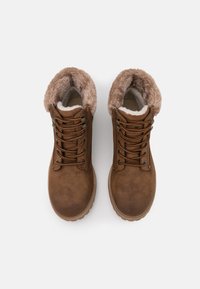 Bottines en cuir marron avec doublure en fausse fourrure, bout arrondi, design à lacets et semelle texturée. Présente des coutures discrètes et des œillets en métal.