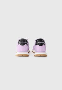 Purple suede sneakers with a black accent heel and white midsole. Features a gum rubber outsole and the brand name on the heel.