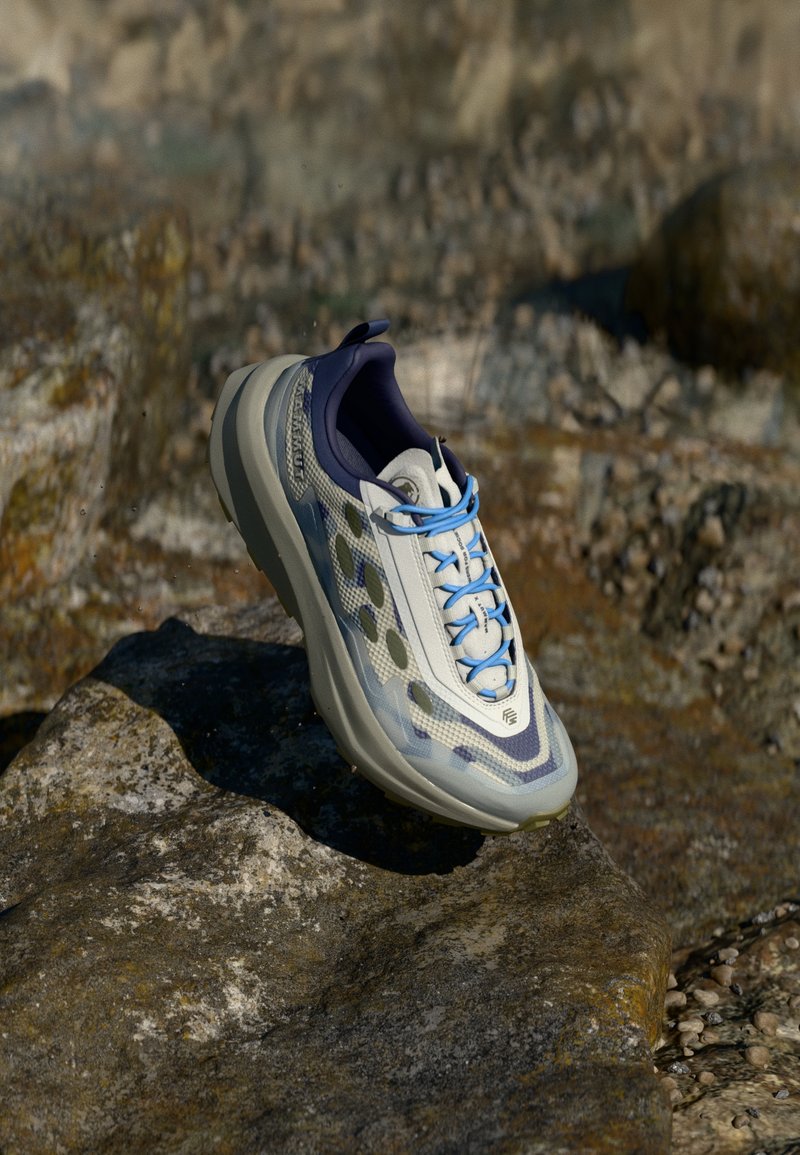 Kogukasv seljal jooksutoss heledas hallis, millel on sinised aktsendid. Võrgust ülemine osa sisaldab tekstuuriga mustrit; paks talla; peegeldavad elemendid nähtavuse suurendamiseks.