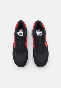 Musta ja punainen lenkkari, jossa on verkkokangasyläosa, mokka-yksityiskohtia, pehmustettu pohja ja mustat nauhat. Valkoinen logo kielekkeessä.