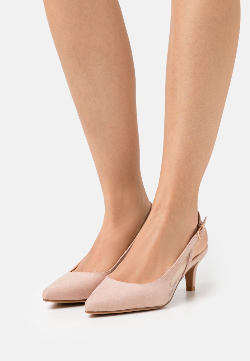 Talons slingback en daim rose avec un embout pointu et un petit talon cylindrique. Présente une sangle réglable avec un détail de boucle en or.