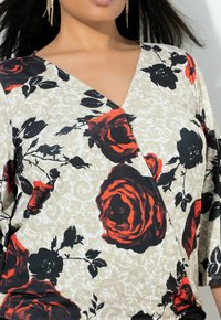Květinová blůza s krémovým pozadím a červenými a černými růžemi, V-výstřihem a tříčtvrtečními rukávy. Hladká látka s paisley vzorem.