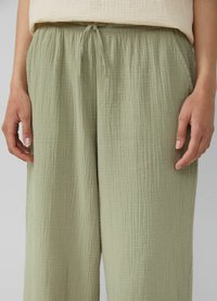 Lichtgroene, gestructureerde wijde broek met een elastische tailleband en trekkoord. De stof lijkt zacht en ademend met subtiele plooien.