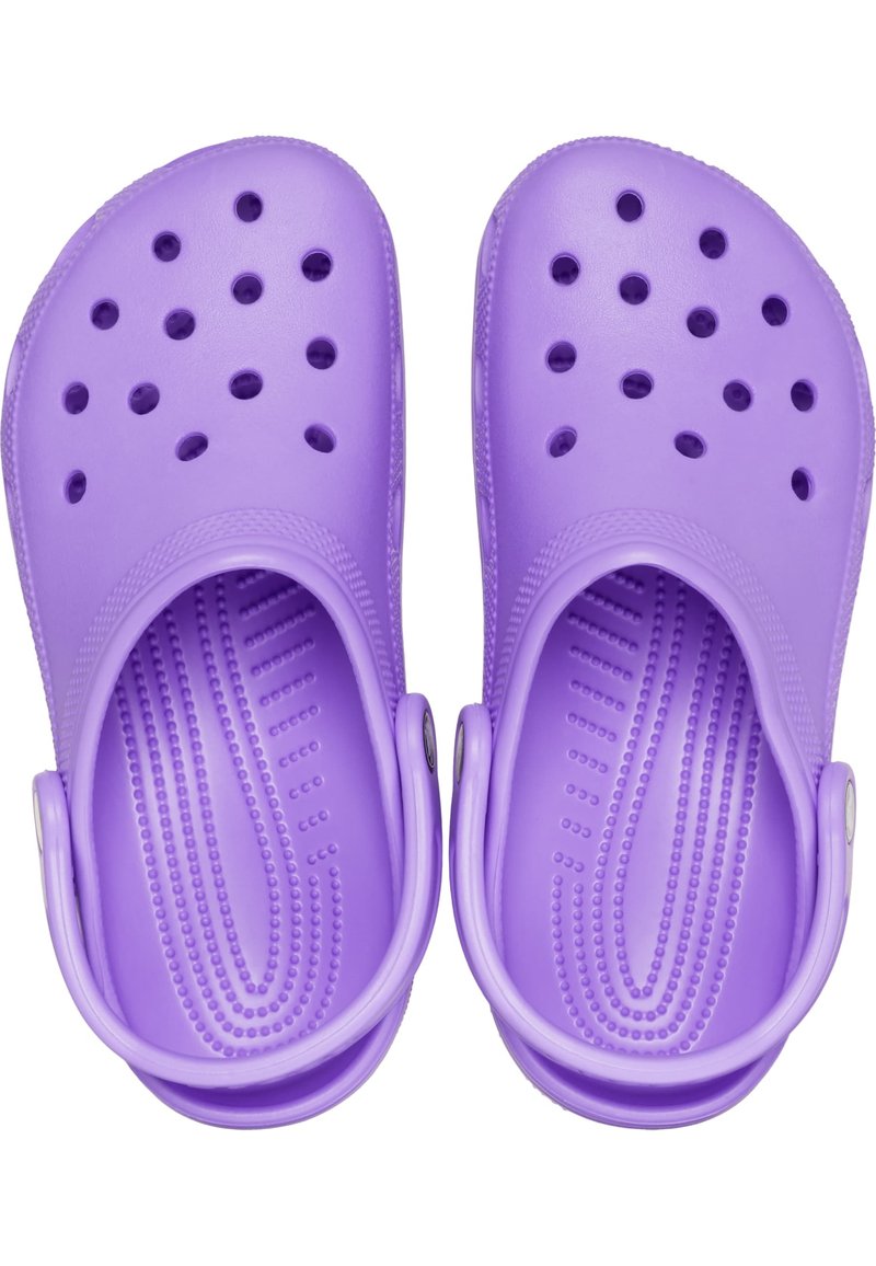 Zuecos morados con un acabado de plástico suave, orificios circulares para ventilación, textura en la base del pie elevada y correas traseras ajustables.