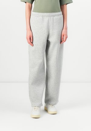 Grå joggebukser laget av myk bomullsblanding med elastisk midje, løs passform og sidelommer. Sammen med hvite sneakers.