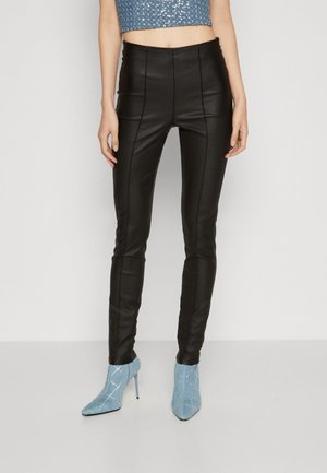 Pantalons en simili cuir noir à coupe slim avec des coutures avant, associés à des bottines texturées bleu clair avec des accents en argent.