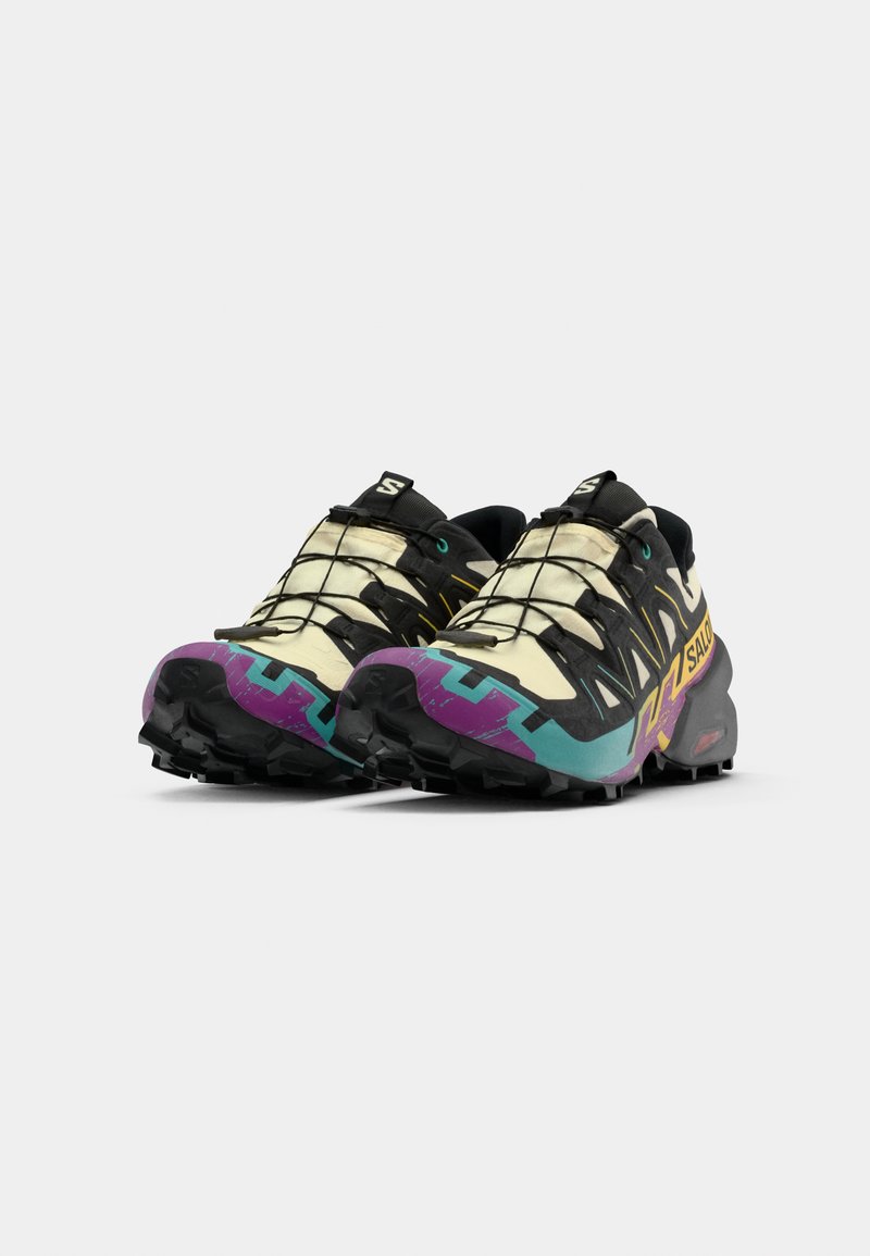 Multicolore trailrunning schoenen met een hoofdzakelijk crèmekleurige bovenzijde, zwarte veters, paarse en teal accenten, en een robuuste zwarte buitenzool.