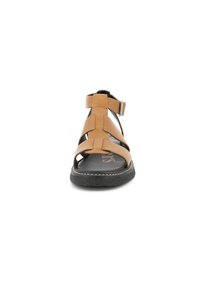 Sandales en cuir marron avec des lanières cousues en croix, bout ouvert, boucle à la cheville, semelle texturée noire et surpiqûres blanches contrastantes.