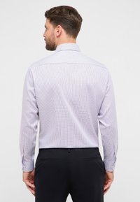 Overhemd met lange mouwen in een lichtpaarse stof met een geruit patroon in donkerpaars en marineblauw. Voorzien van een klassieke kraag en knoopmanchetten.