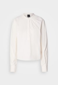 Blusa bianca a maniche lunghe con colletto rotondo e pattina dei bottoni, caratterizzata da sottili righe verticali, mostrata su uno sfondo neutro.
