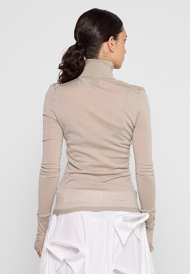 Beige Langarm-Turtleneck-Oberteil aus geripptem Stoff, figurbetontes Design mit glatter Textur. Verfügt über einen hohen Kragen und schmale Ärmel.
